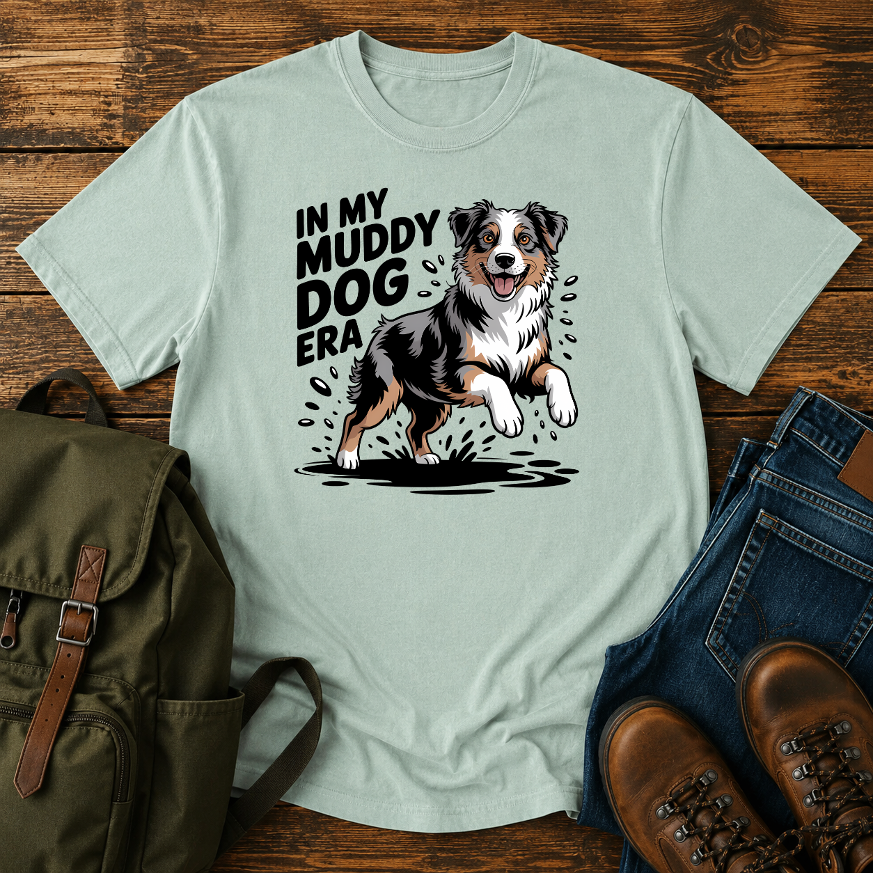 Australian Shepherd dog shaking off muddy creek water on a retro outdoor t-shirt design.