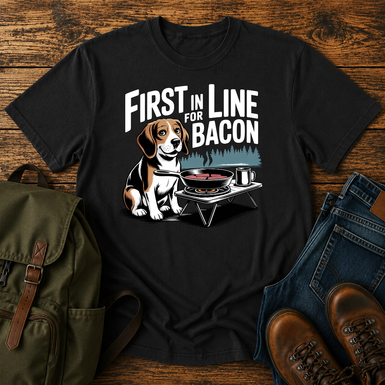 Beagle beside cast-iron skillet on camp stove with tin mug and enamel plate on t-shirt