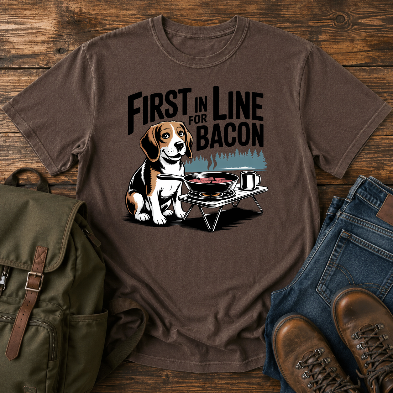 Beagle beside cast-iron skillet on camp stove with tin mug and enamel plate on t-shirt