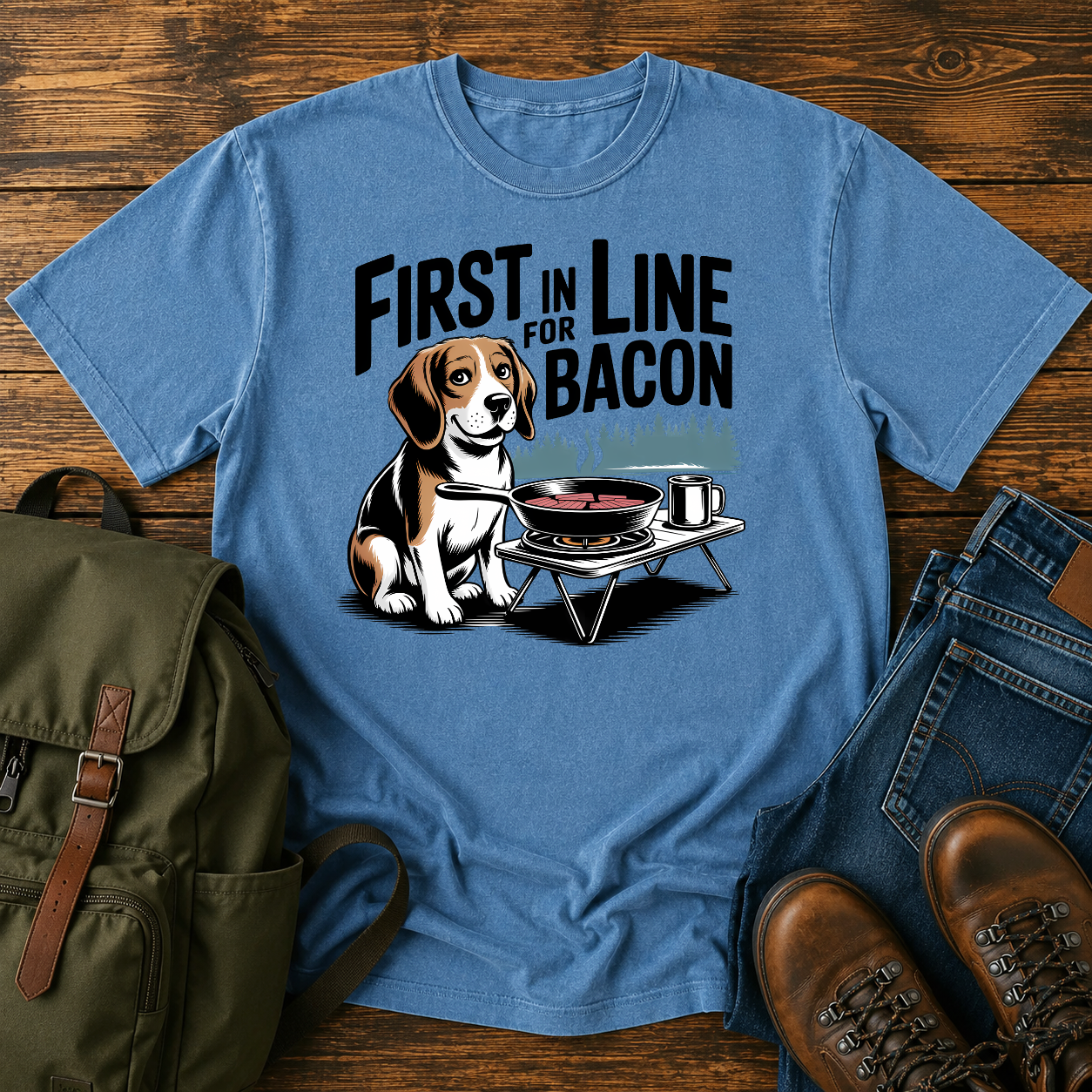 Beagle beside cast-iron skillet on camp stove with tin mug and enamel plate on t-shirt