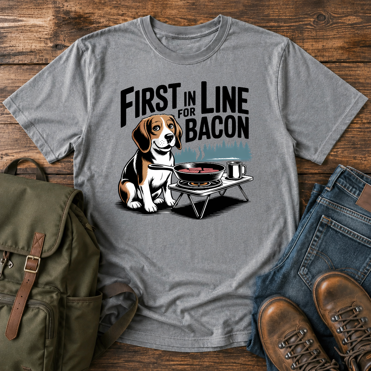 Beagle beside cast-iron skillet on camp stove with tin mug and enamel plate on t-shirt