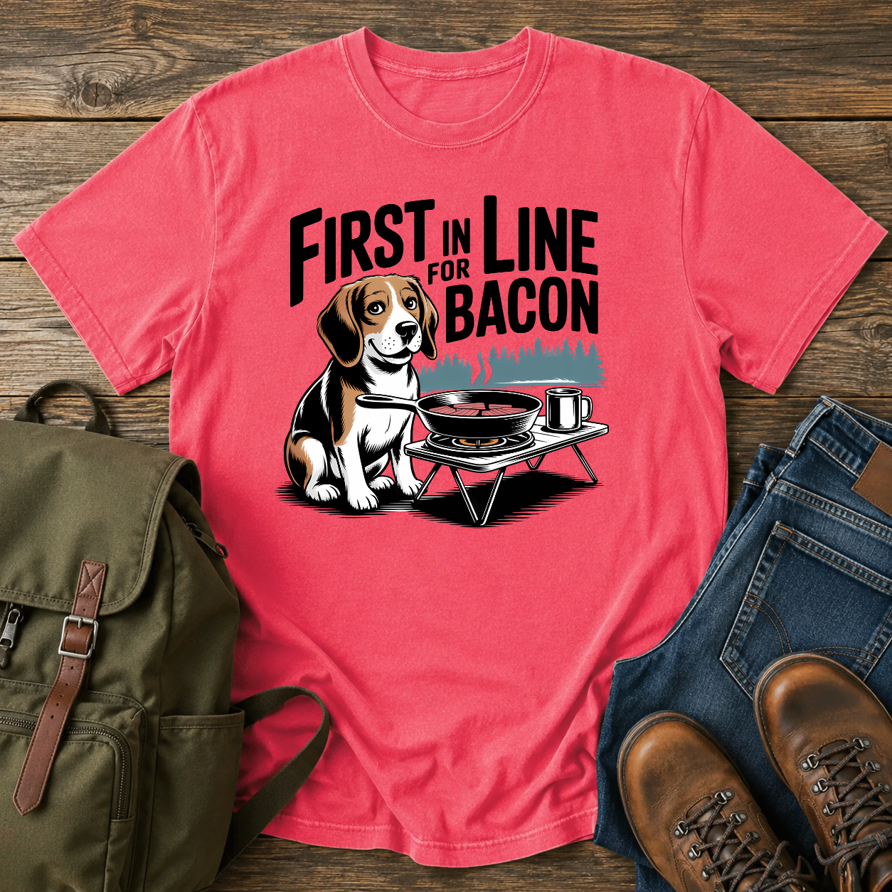 Beagle beside cast-iron skillet on camp stove with tin mug and enamel plate on t-shirt